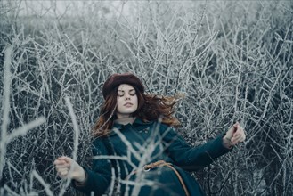 Caucasian woman laying on branches in winter field