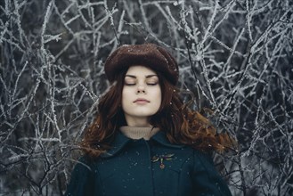 Caucasian woman with eyes closed near icy branches