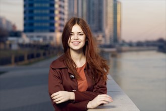 Smiling Caucasian woman leaning on wall at waterfront