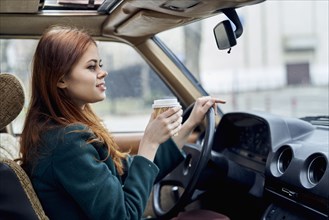 Caucasian woman driving car and drinking coffee