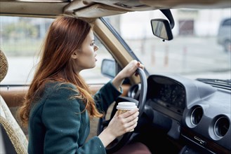 Angry Caucasian woman driving car and drinking coffee