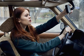 Caucasian woman driving car adjusting mirror