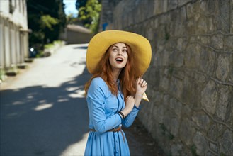 Surprised Caucasian woman wearing hat near stone wall