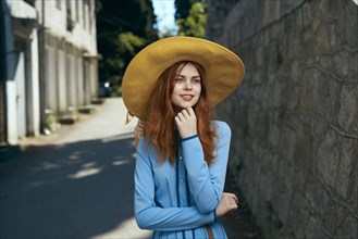 Pensive Caucasian woman wearing hat near stone wall