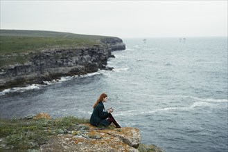 Caucasian woman examining camera near ocean