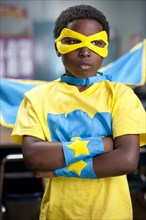 African American boy wearing superhero costume in classroom