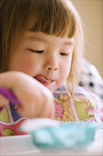 Close up of young girl eating in high chair