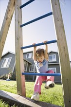 Young girl playing on play structure in back yard
