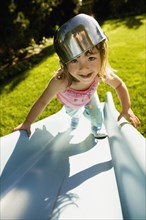 Portrait of girl climbing slide with bowl on head