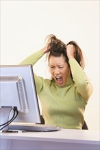 Frustrated businesswoman pulling on hair in front of computer