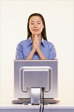 Businesswoman praying in front of computer