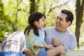 Hispanic father and daughter laughing outdoors