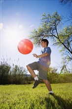 Boy kicking ball in bright sunlight