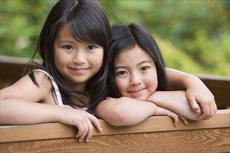Young Asian sisters hugging and smiling outdoors