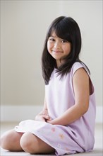Young Asian girl sitting on floor smiling