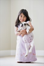 Young Asian girl smiling and holding puppy
