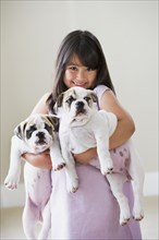 Young Asian girl smiling and holding two puppies