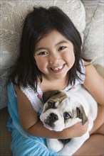 High angle view of young Asian girl holding puppy