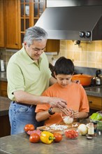 Hispanic father and son chopping vegetables in kitchen