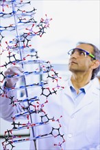 Indian male scientist holding DNA model