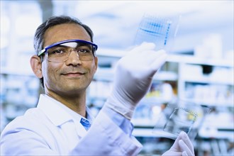 Indian male scientist smiling and holding DNA film