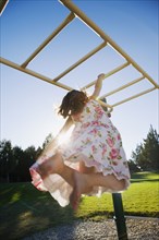 Asian girl hanging on play structure