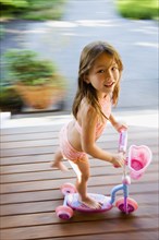 Asian girl riding foot powered scooter
