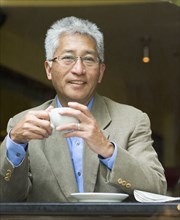 Senior Asian businessman holding cup of coffee
