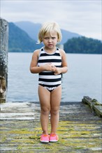 Young girl in bathing suit standing on wooden pier