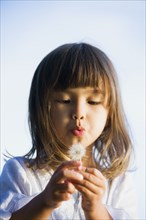 Asian girl blowing a dandelion