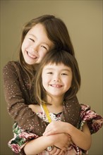Portrait of Asian sisters hugging