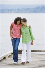 African American mother and adult daughter walking on pier
