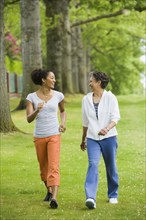 African American mother and adult daughter walking in park