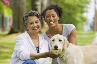 African American mother and adult daughter petting dog