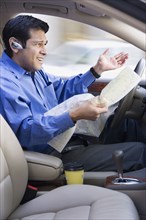 Hispanic businessman looking at map and driving