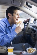 Hispanic businessman eating and driving