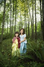 Asian sisters wearing costumes in woods
