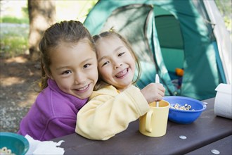 Asian sisters eating at campsite