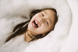 Asian girl laughing in bubble bath