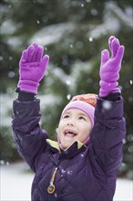 Asian girl with arms raised in snow