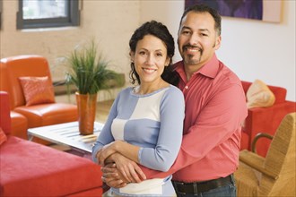 Hispanic couple hugging in livingroom