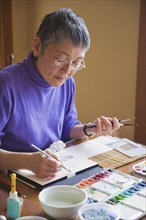 Asian woman painting at table