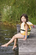 Asian girl in life jacket on dock