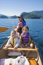 Mother and daughters rowing canoe on lake