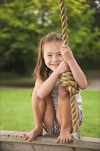 Asian girl swinging on rope swing