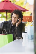 Middle Eastern man with shopping bags talking on cell phone