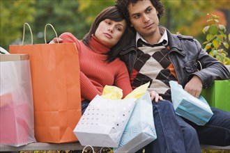 Exhausted couple sitting with shopping bags