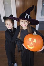 Mixed race young girls in cat and witch costumes