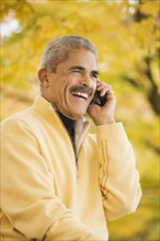 African man using cell phone outdoors in autumn