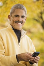 African man using cell phone outdoors in autumn